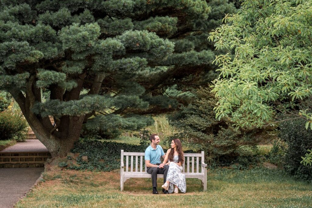 Couple seated on a garden bench during an engagement session at Deep Cut Gardens