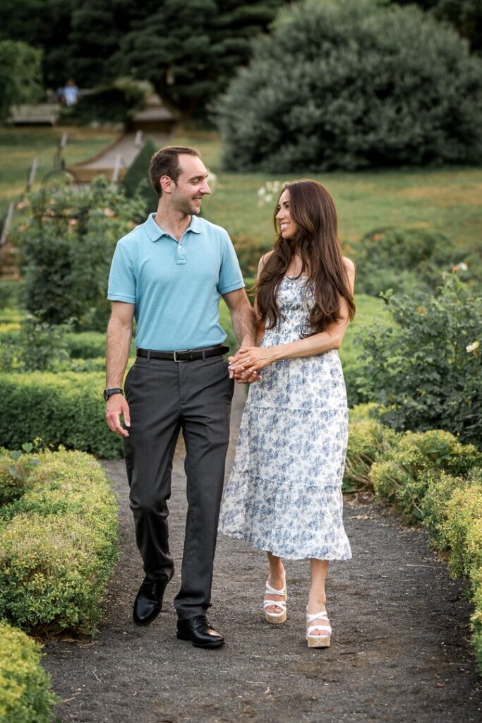 Engaged couple walking the parterre path at Deep Cut Gardens with other visitors nearby