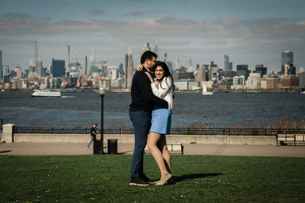 Newly engaged couple embracing on the grass moments after a surprise proposal in New Jersey