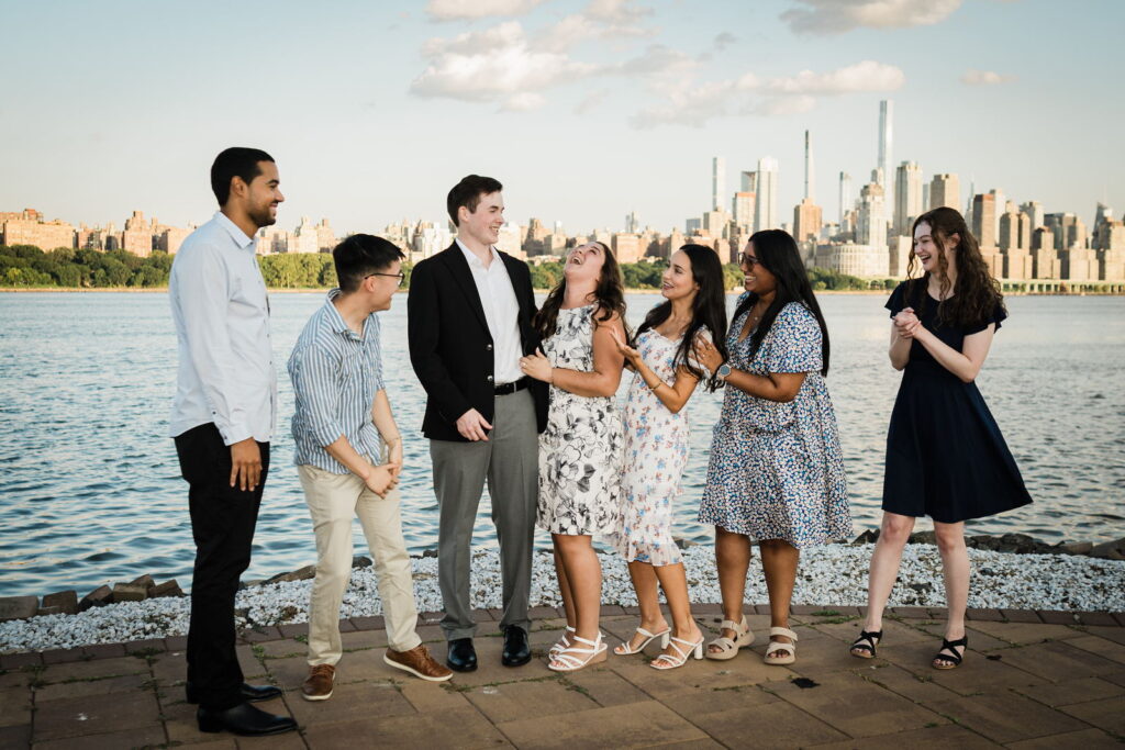 Newly engaged couple celebrating with family and friends on waterfront walkway after proposal