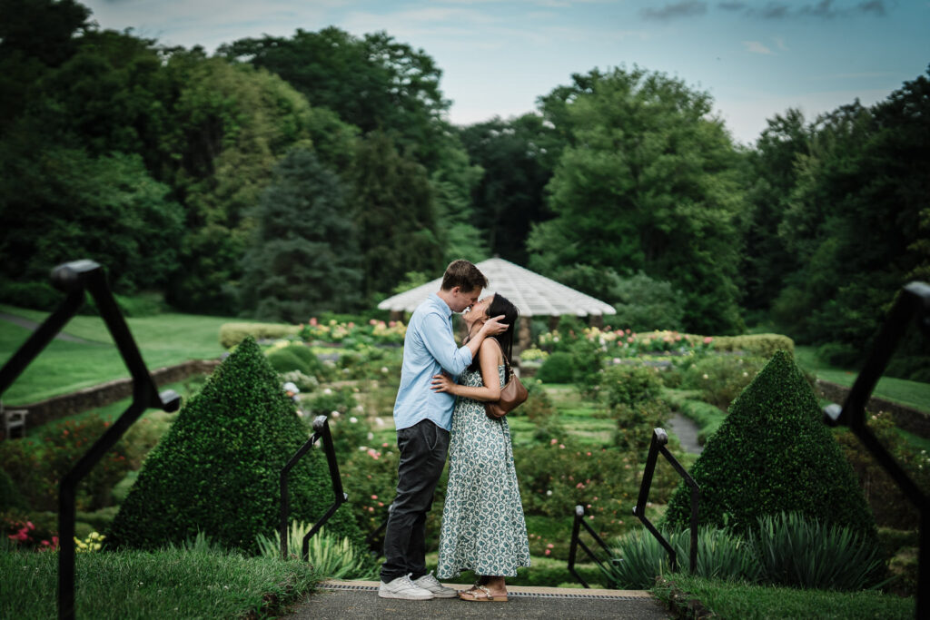 Andrew and Emily kissing at the top of the parterre steps at Deep Cut Gardens