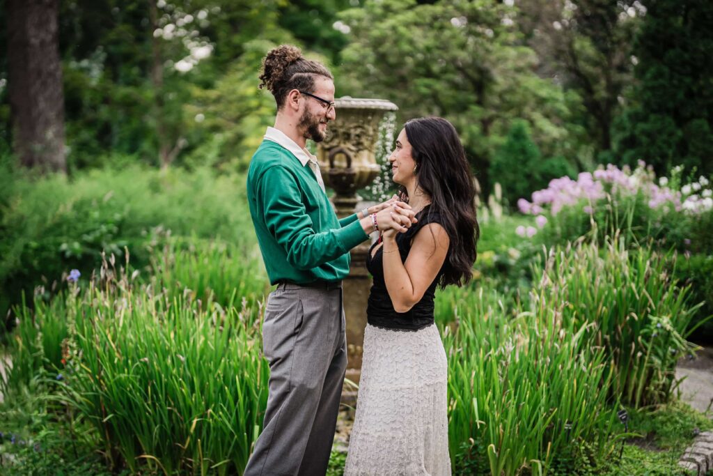 Philip and Lexi holding hands beside a stone fountain urn at Van Vleck Gardens Montclair