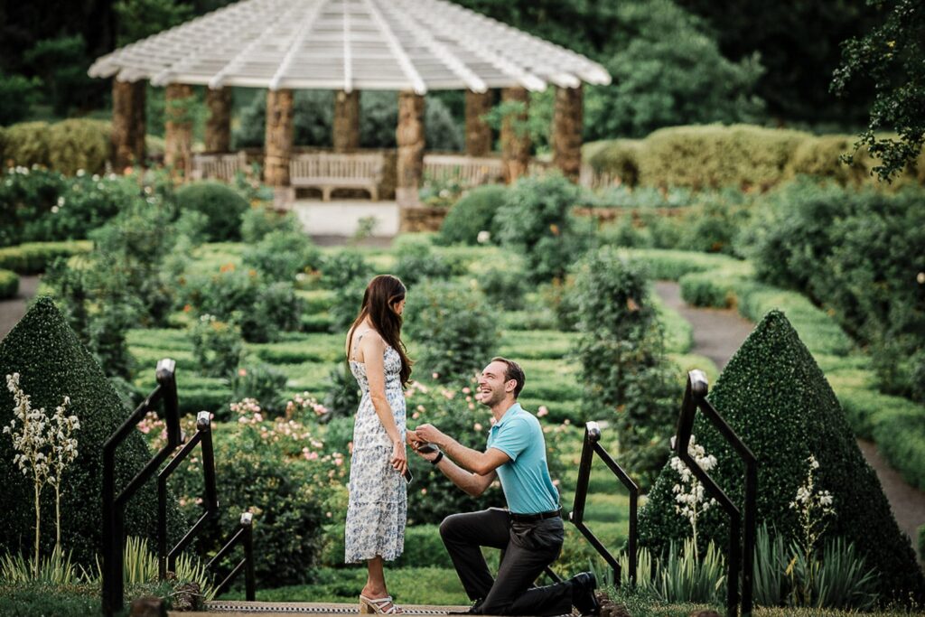 Man kneeling to propose in a formal garden at Deep Cut Gardens in Middletown New Jersey