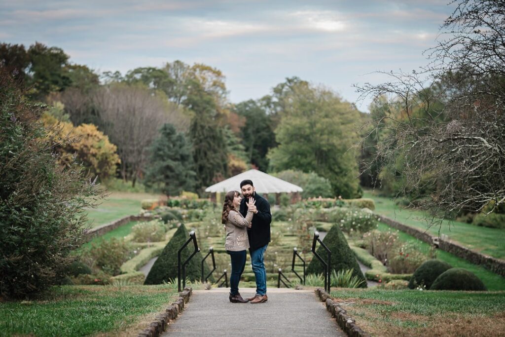 Couple celebrating a golden hour proposal on the parterre path at Deep Cut Gardens