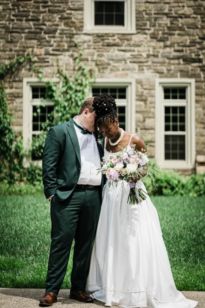 Newlywed portrait outside the stone facade of Alverthorpe Manor in Jenkintown