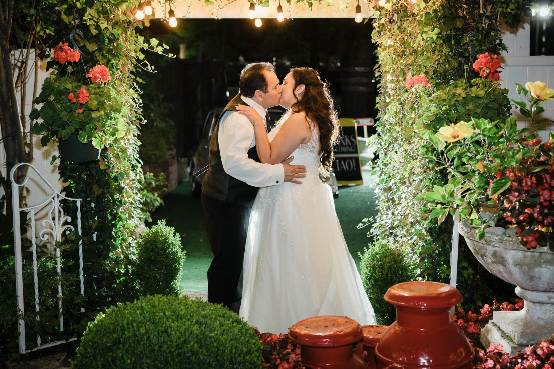 Bride and groom kissing beneath the garden arch at Piazza di Roma