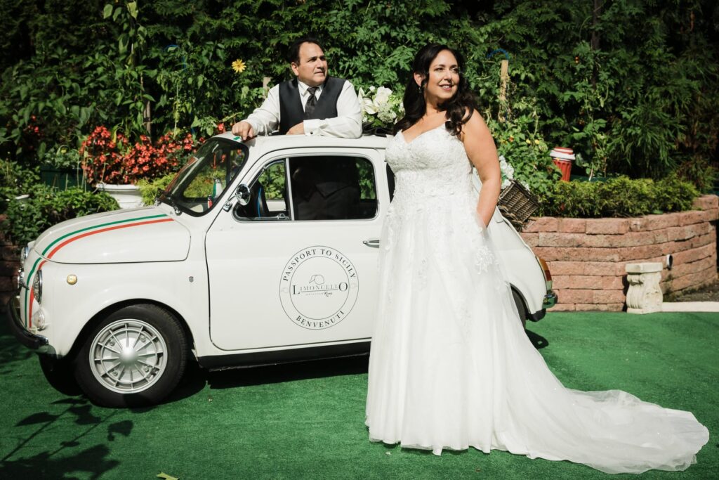 Bride leaning against a vintage Fiat on the lawn at Piazza di Roma