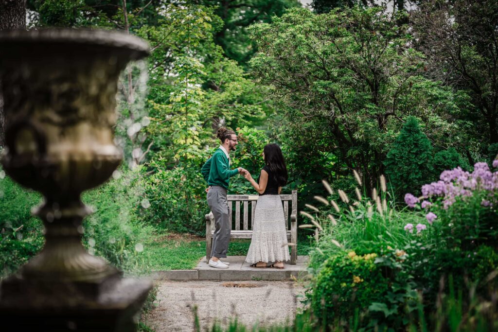 Philip and Lexi at a secluded garden bench seen through the beds at Van Vleck