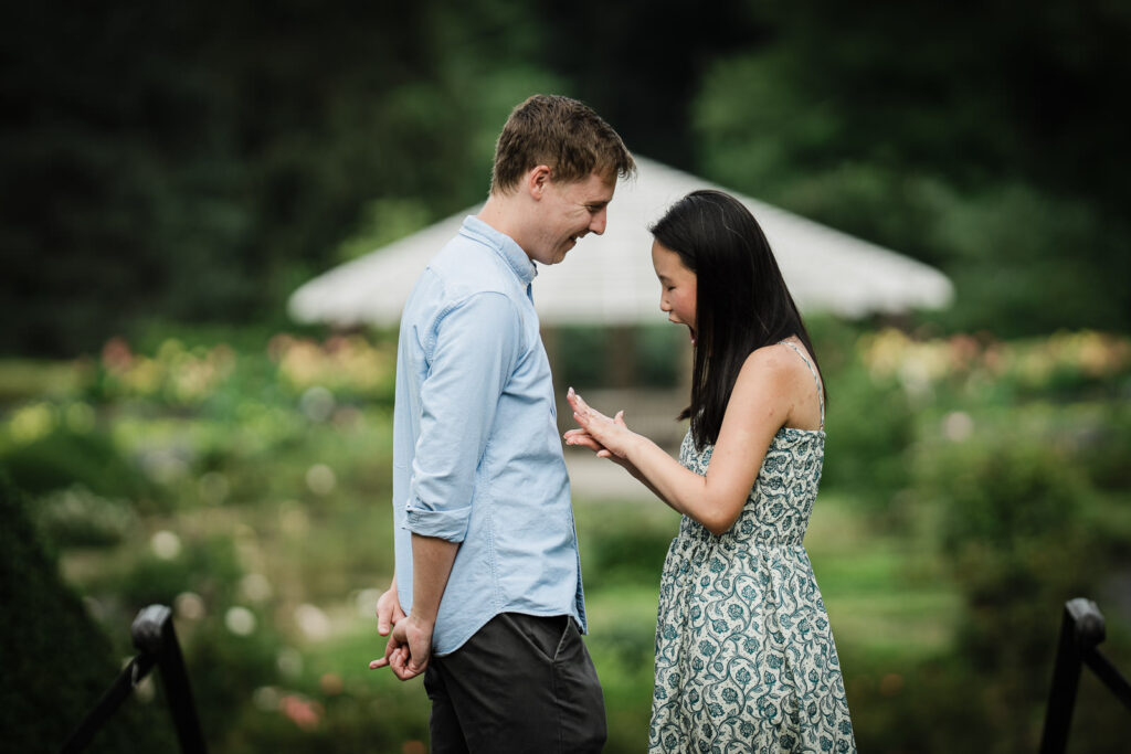 Emily looking at her engagement ring beside Andrew at Deep Cut Gardens in Middletown