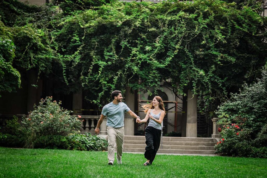 Newly engaged couple walking hand in hand across the lawn at Van Vleck House