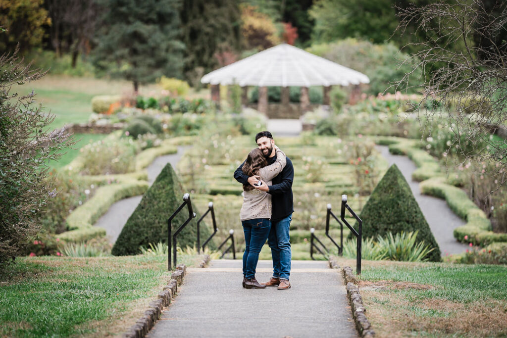 Newly engaged couple embracing in a garden moments after a surprise proposal in New Jersey