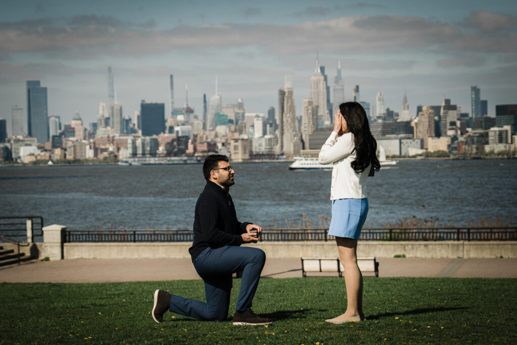 Surprise proposal on a waterfront lawn with the New York City skyline in the background