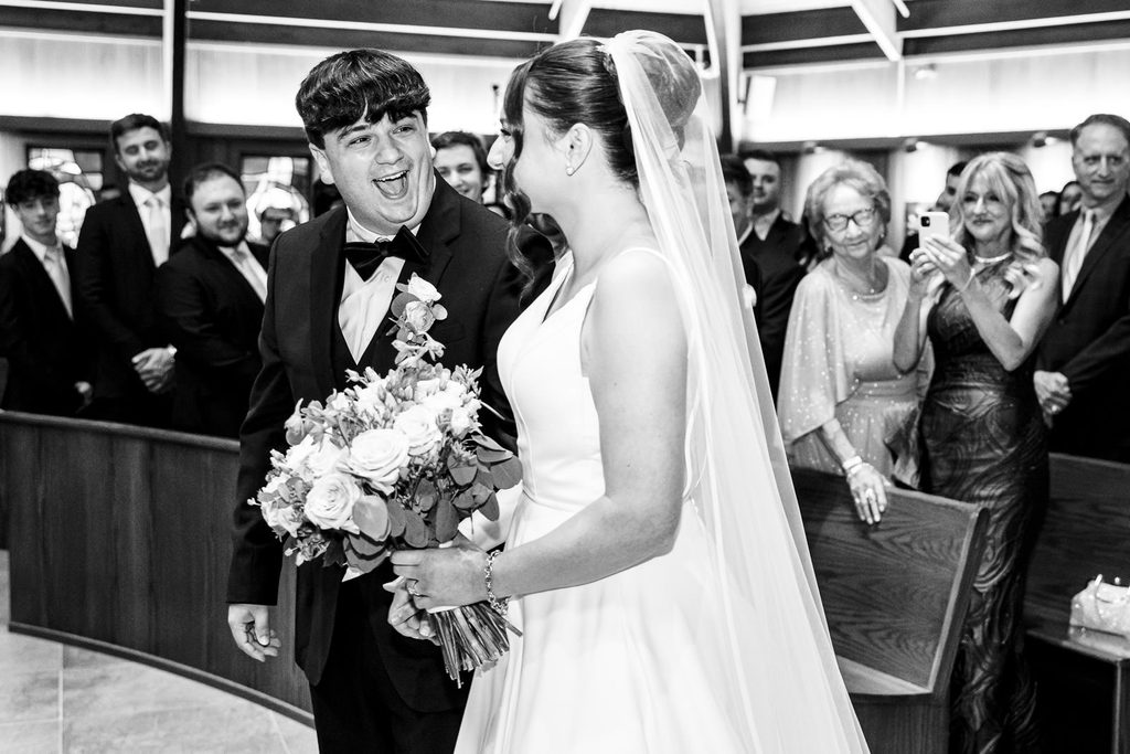 Groom laughing with joy as his bride reaches the front of a New Jersey church ceremony
