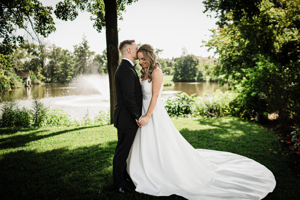 James kissing Ilysse on the forehead beside the lake at Brooklake Country Club
