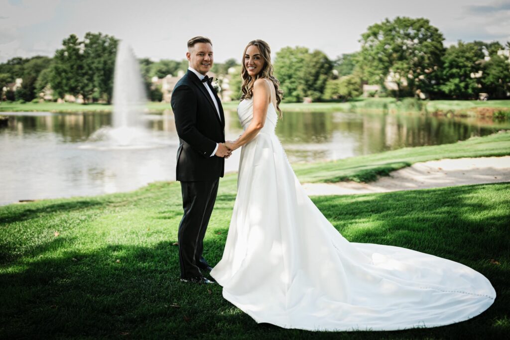 Ilysse and James posing beside the lake during their Brooklake Country Club wedding