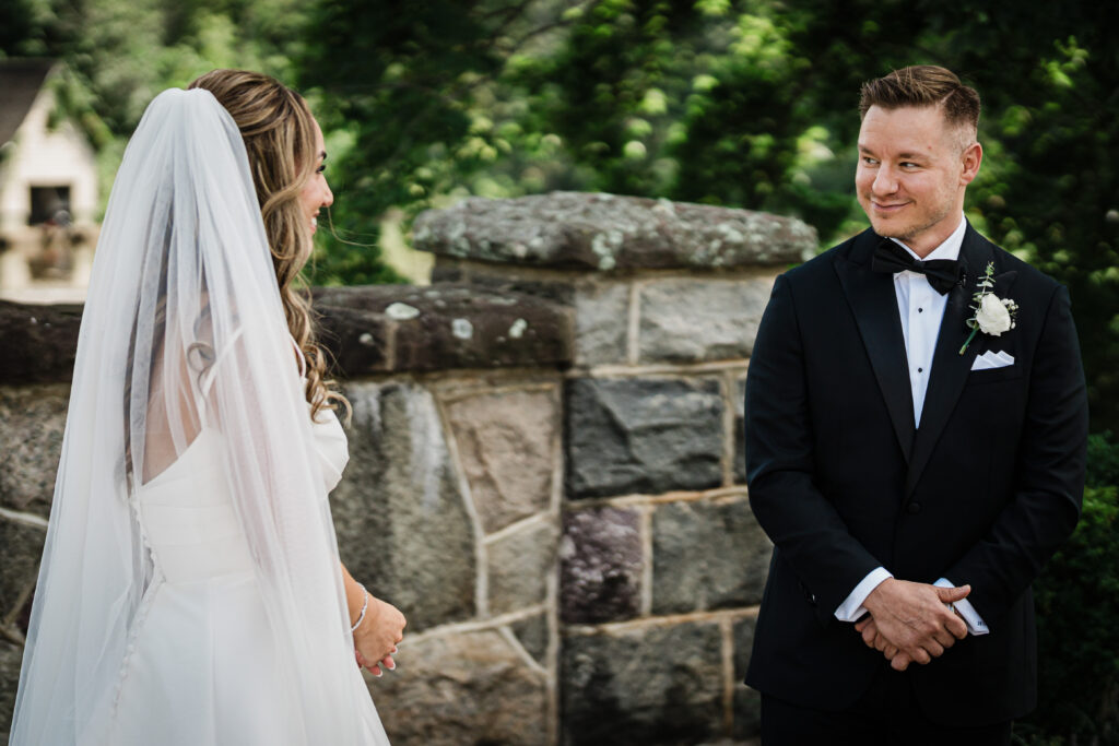 Ilysse and James during their first look beside the stone wall at Brooklake Country Club