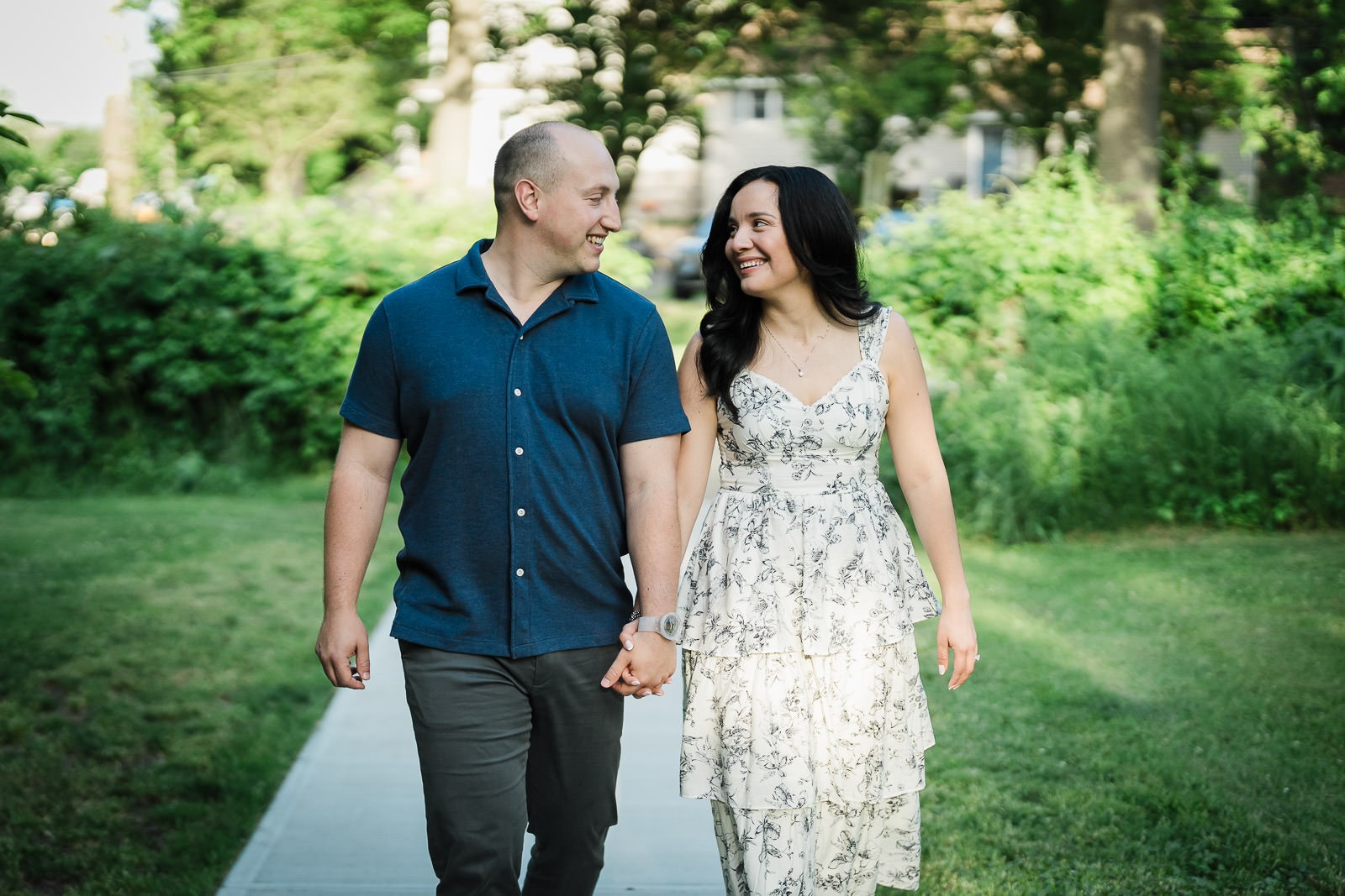 Engaged couple walking hand in hand and laughing together at Burnham Park in Morristown NJ