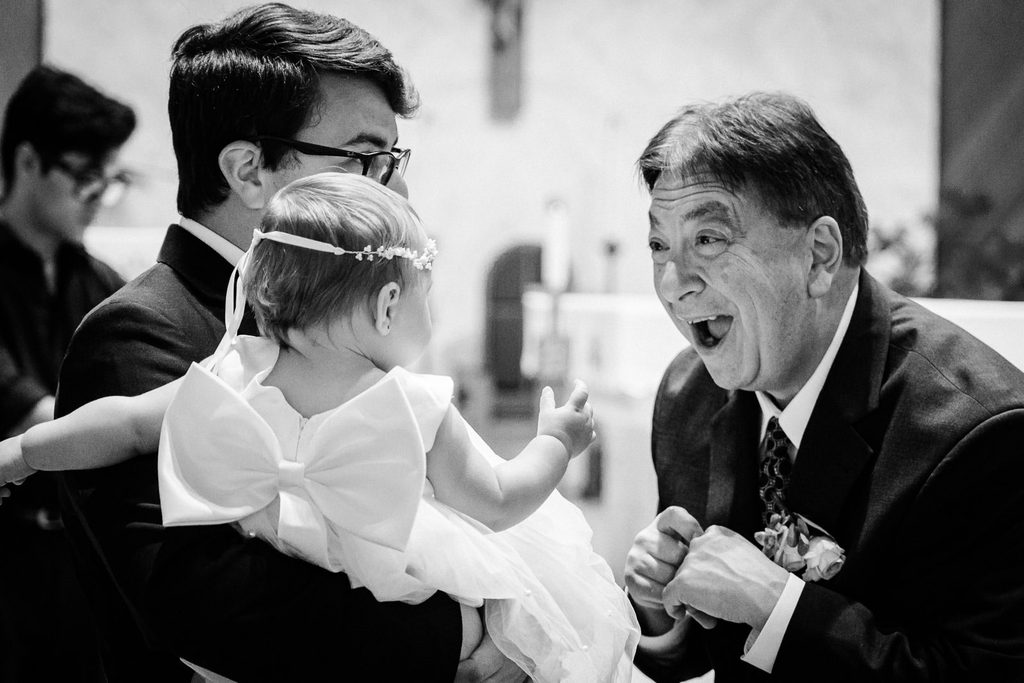 Older guest delighting a baby girl during a Mansion at Mountain Lakes wedding ceremony