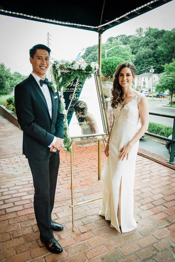 Bride and groom photographed under a covered venue entrance during rain in New Jersey