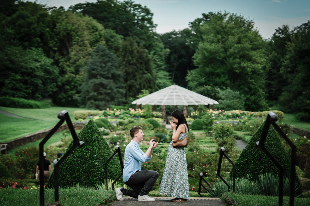 Couple in summer engagement outfits during proposal at Deep Cut Gardens Middletown NJ