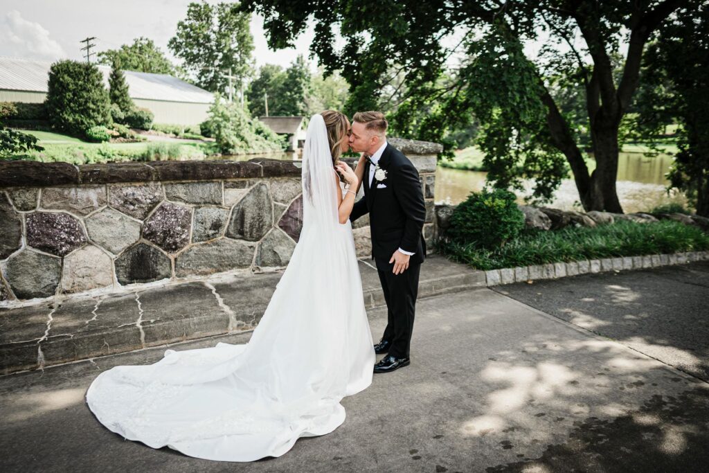 Ilysse and James embracing beside the stone wall during their Florham Park NJ wedding