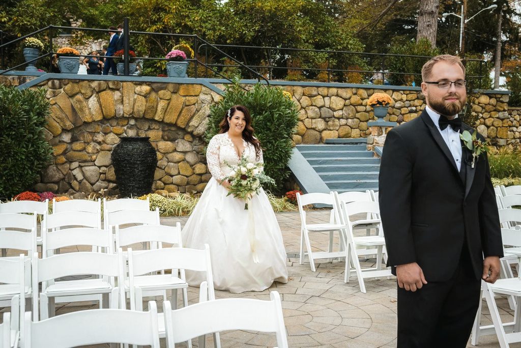 Bride walking toward groom during a first look in the ceremony space at Ramsey Country Club