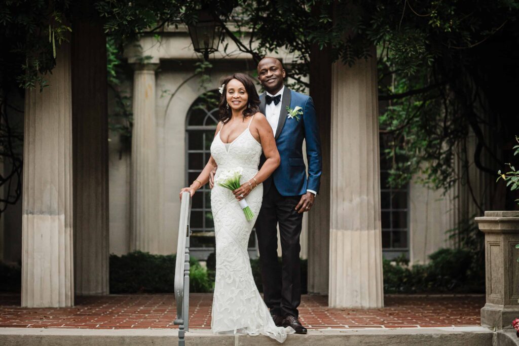 Allison and Pascal on the brick portico beneath wisteria at Van Vleck Gardens