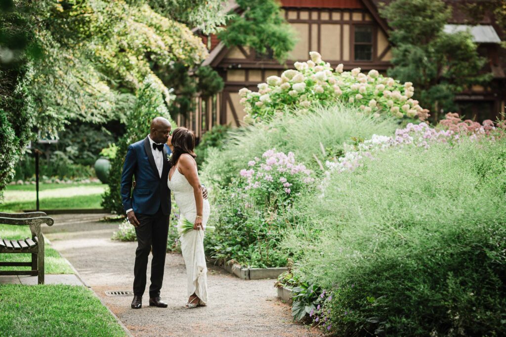 Allison and Pascal kissing on a flower bordered path at Van Vleck