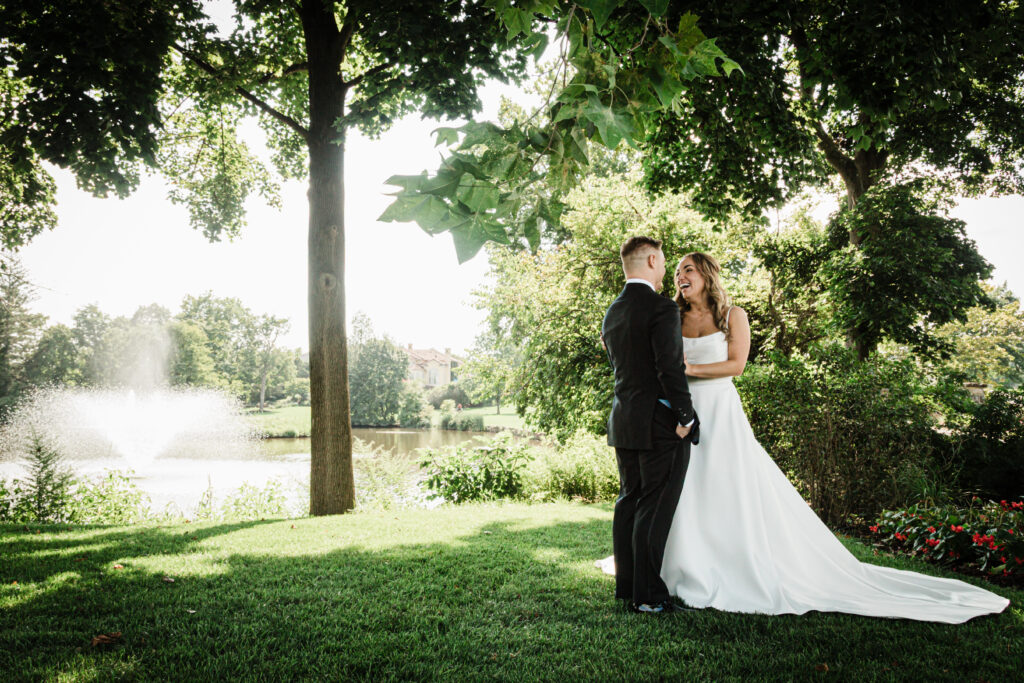 Ilysse laughing beside the lake and fountain at their Florham Park NJ wedding
