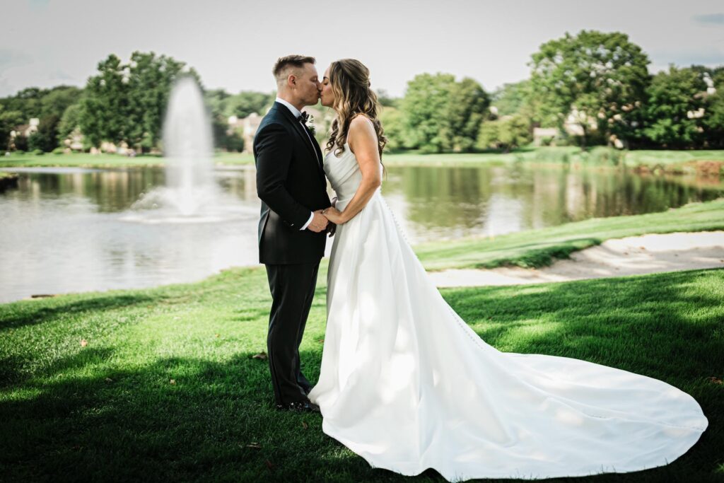 Bride and groom close together beside the lake at Brooklake Country Club