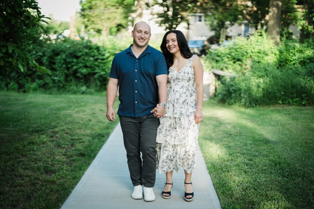 Engaged couple holding hands on a garden path at Burnham Park in Morristown NJ