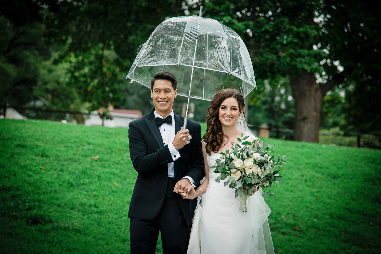 Bride and groom under a clear umbrella during rain at a New Jersey wedding