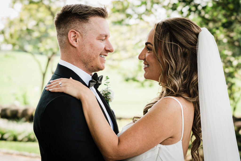 Ilysse and James smiling at each other during portraits at Brooklake Country Club