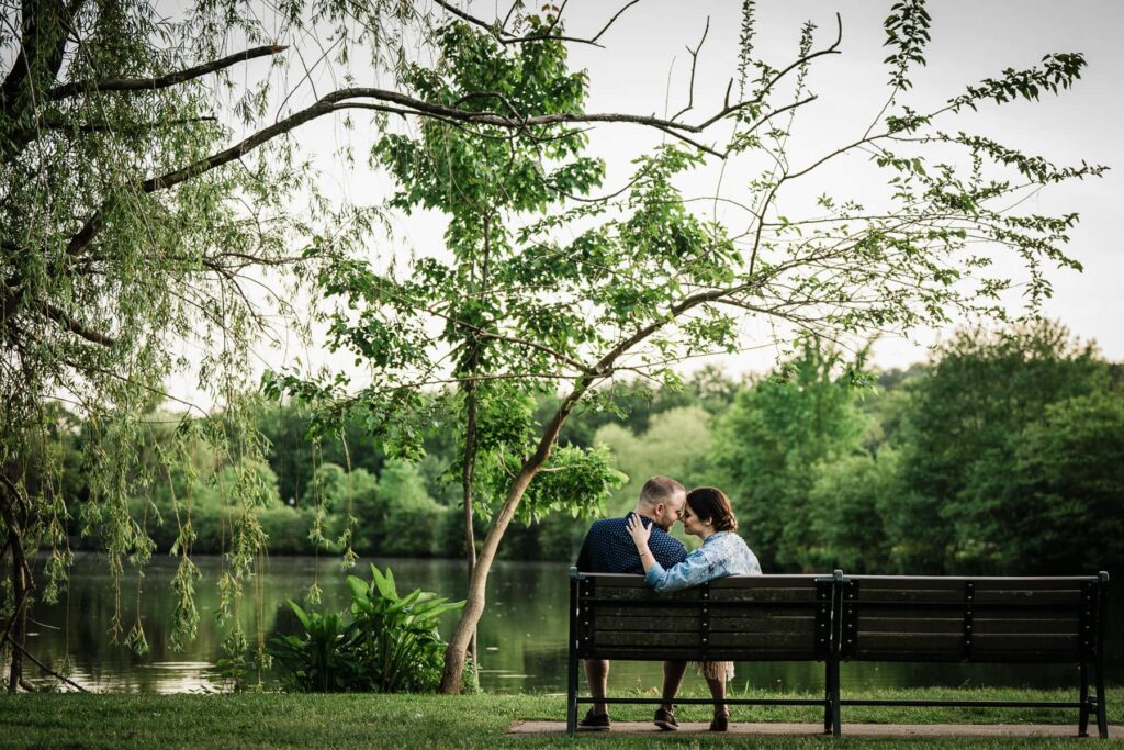 Engaged couple sitting on a bench during a summer session at Verona Park