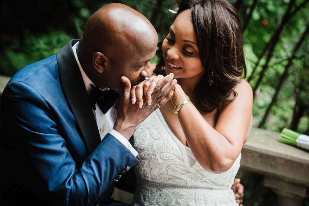 Groom kissing the bride's hand in the gardens at Van Vleck Montclair NJ