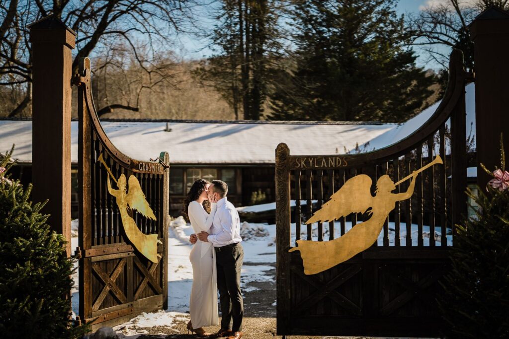 Couple kissing at the Skylands entrance gates during a winter engagement session in Ringwood NJ