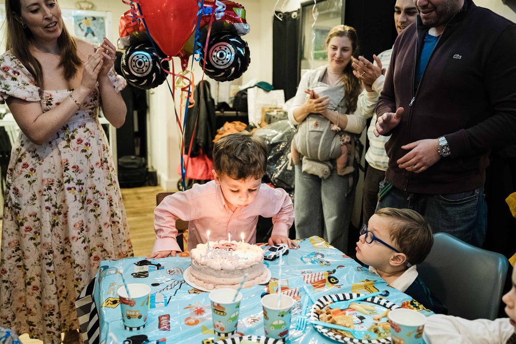 Child blowing out birthday candles as family cheers at Crossbar NYC