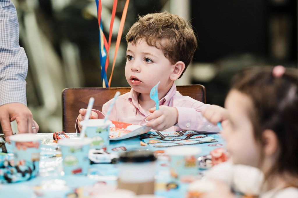 Child eating birthday cake at the party table during a Crossbar NYC celebration