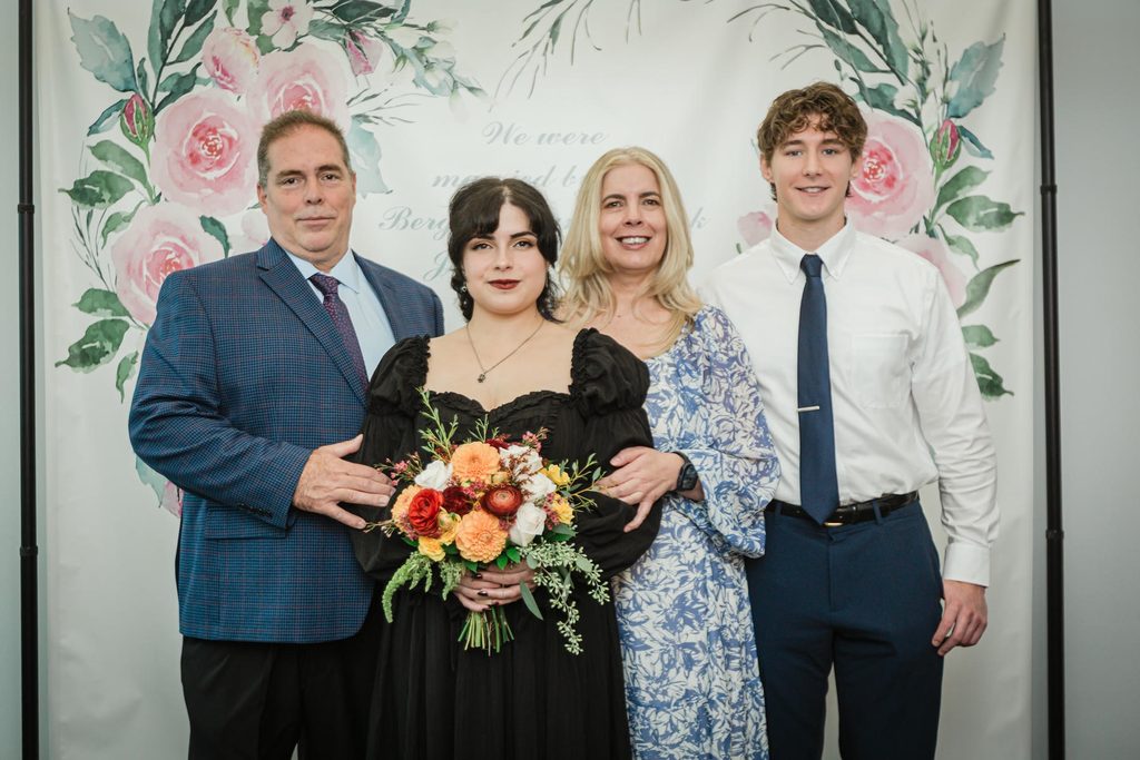 Family group portrait with the newlyweds in front of a floral backdrop at a Hackensack courthouse