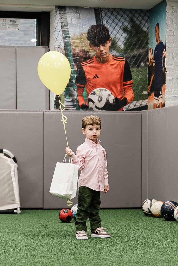Child standing on the indoor soccer field during a birthday celebration at Crossbar NYC