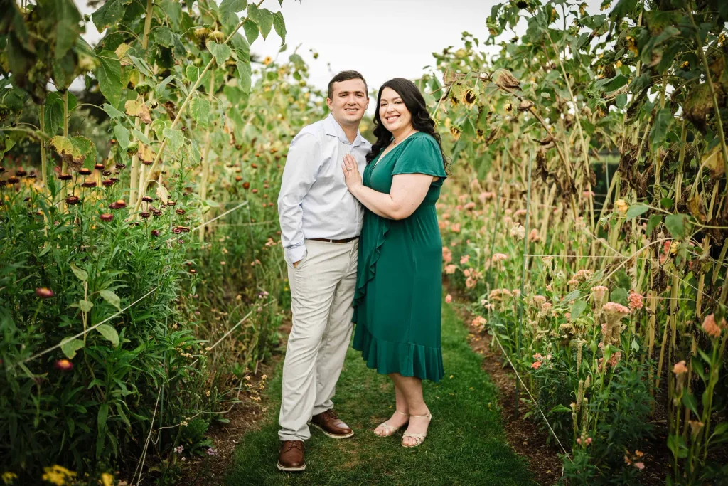 Engaged couple standing between flower rows in the Cutting Garden at Harkness