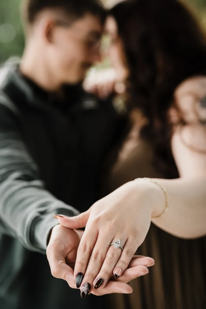 Engagement ring close-up with the couple softly blurred behind during Bell Works session