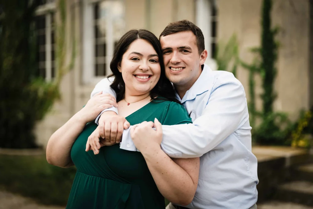 Engaged couple hugging in front of Eolia mansion at Harkness Memorial State Park