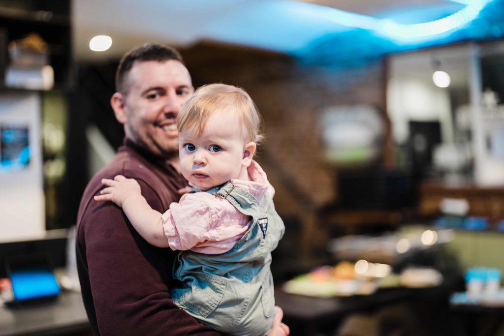 Father holding his young child during a family birthday celebration in NYC