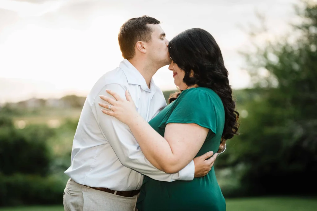 Man kissing his partner's forehead during a Connecticut coastal engagement session at Harkness