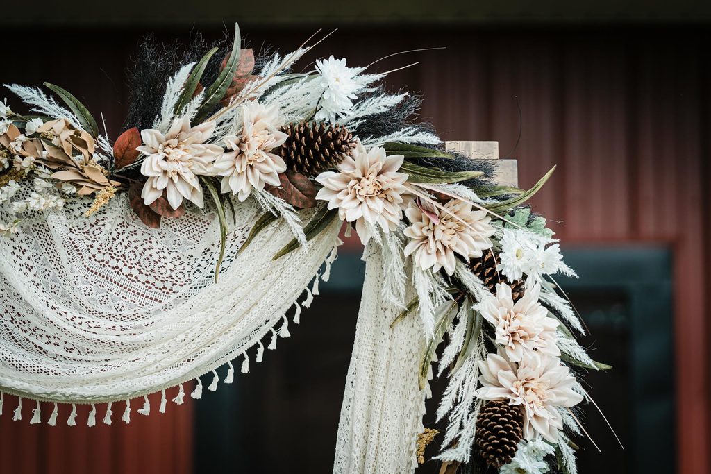 Floral ceremony arch in front of a red barn at a Franklin Township backyard wedding