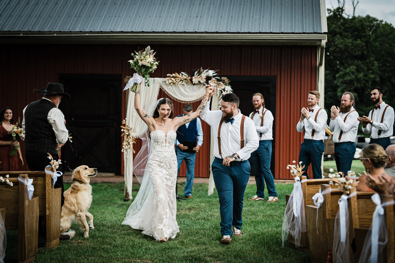 Bride and groom raising hands after their Franklin Township backyard wedding ceremony by a red barn