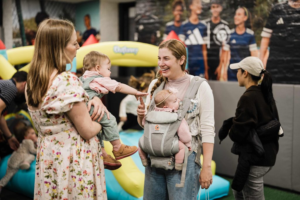 Mother holding her baby while greeting a guest and infant at Crossbar NYC