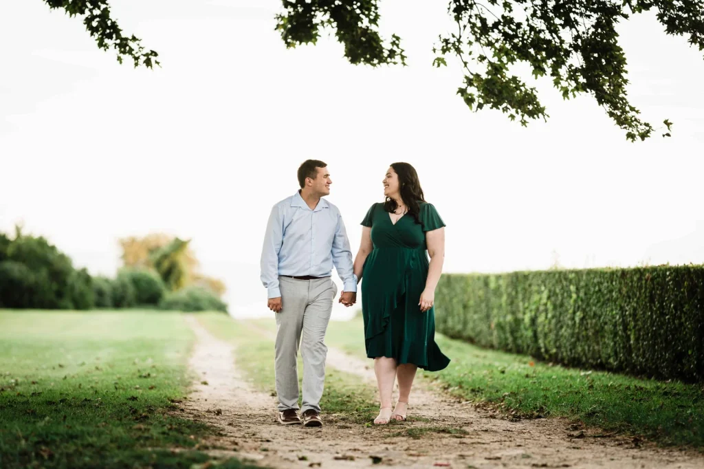 Engaged couple walking a hedge lined path at Harkness Memorial State Park