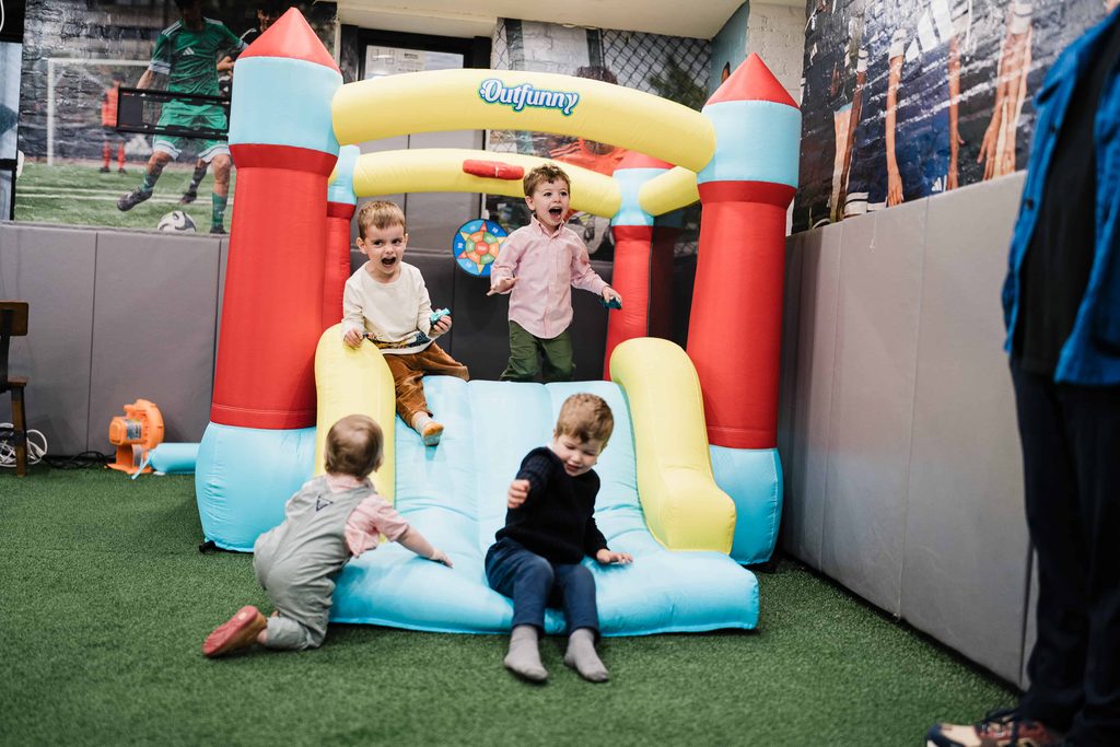 Children playing on a bounce house slide during a kids birthday party at Crossbar NYC
